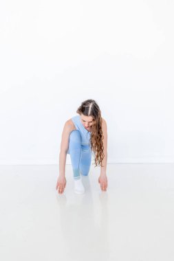 Yoga yapan genç bir kadın kollarının üzerinde duruyor ve bacaklarını açıyor. Sağlık ve güzellik konsepti. Beyaz çatı katı stüdyo geçmişi