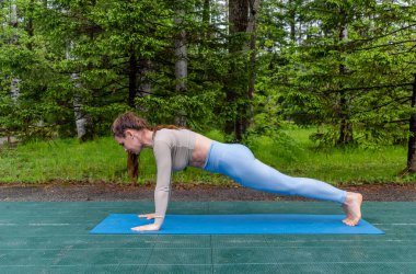 Samimi kızıl saçlı bir kadın parkta yoga yapıyor. Spor giyim ve yoga minderi. Sağlık ve spor yaşam tarzı konsepti. Boşluğu kopyala