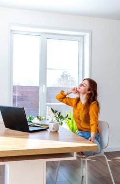 Genç iş kadını işten sonra internetten bilgisayar kullanarak meditasyon yapıyor. Dişi kız dizüstü bilgisayarın yanında sakin müzik dinler. Ev konforu ve ruh sağlığı konsepti.