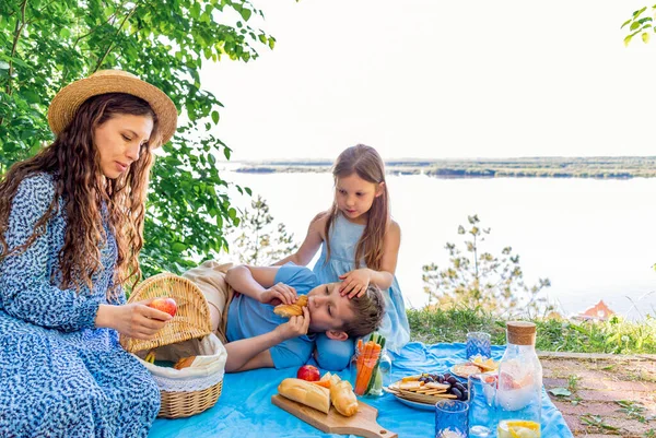 Family outdoor picnic. Mom and the children are eating lunch in nature. Wellness concept. Healthy food for people.