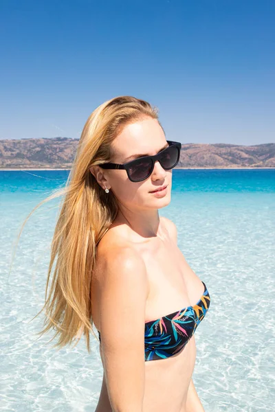 Retrato de menina sexy em óculos de sol em pé na praia de um lago de montanha. Jovem mulher vestindo maiô sexy — Fotografia de Stock