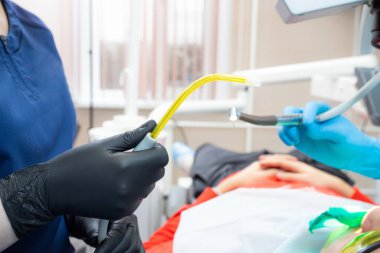 Diş hekimi asistanı diş tedavisi sırasında tükürük püskürtücüye yardım ediyor