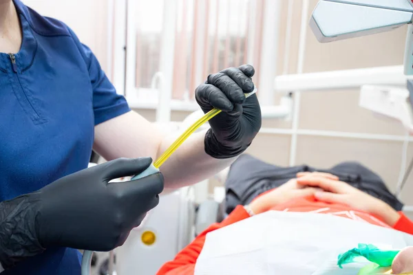 Dental assistant helping with saliva ejector during dentist treatment