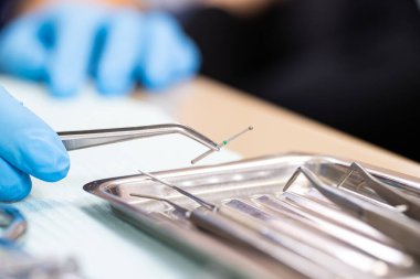 Diş aletleri kapanıyor. Dişçi, matkap için cımbızla matkap tutuyor. Diş tedavisi.