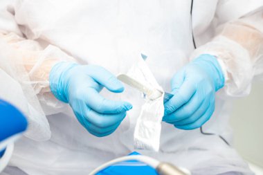 Dişçi implantasyon ameliyatı sırasında tek kullanımlık steril neşter açar.