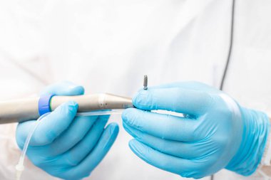 Diş implantı ameliyatı sırasında aleti dişçi tutuyor.