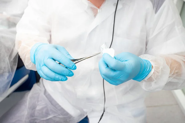 Médico dentista sosteniendo fórceps quirúrgicos, aguja de sutura, grapas — Foto de Stock