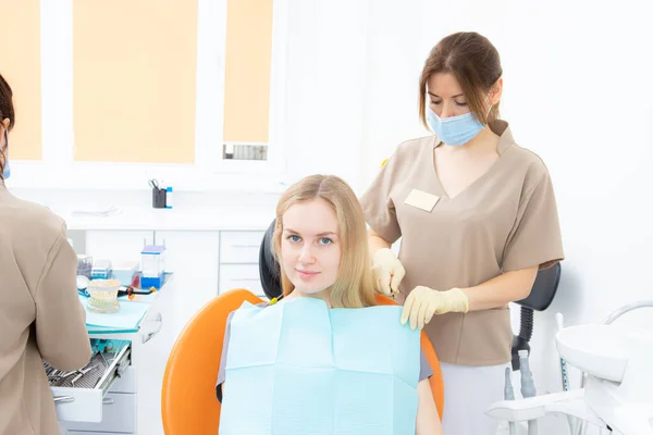 Ассистент стоматолога перед началом лечения накладывает защиту на пациента — стоковое фото