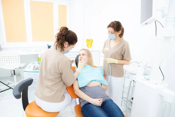 Беременная женщина в кабинете стоматолога, осмотр и стоматологическое лечение беременных женщин. — стоковое фото
