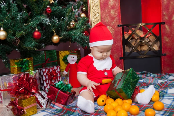 Bambino in costume da Babbo Natale vicino a un albero di Natale — Foto Stock