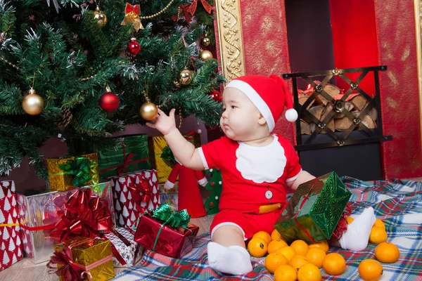 Baby in Santa costume near a Christmas tree — Stock Photo, Image