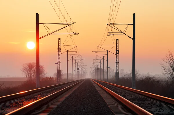 Railway at sunset with sun — Stock Photo, Image