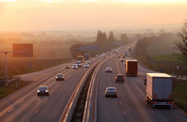 Bilar på motorvägen road vid solnedgången — Stockfoto