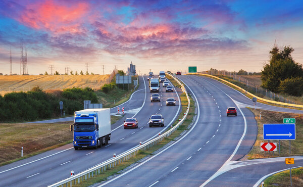 Highway traffic in sunset with cars and trucks