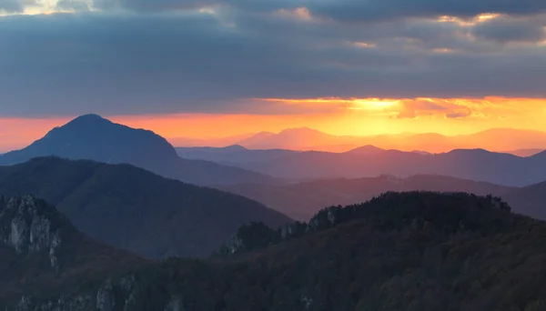Raios de pôr do sol dramáticos atrás da silhueta de de montanha — Fotografia de Stock