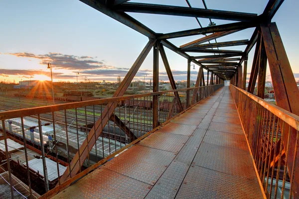 Ponte de pé sobre a ferrovia ao pôr do sol — Fotografia de Stock