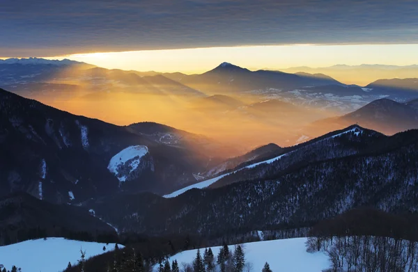 Solnedgång över färg berg siluett med strålar — Stockfoto