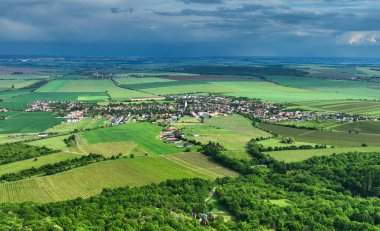 Dark rain cloud with storm over a green field and village