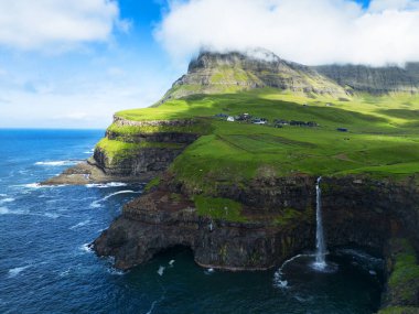 Mulafossur Şelalesi 'nin görkemli sabah manzarası. Vagar Adası, Faroe Adaları, Danimarka, Avrupa 'nın göz kamaştırıcı yaz manzarası. Uçan İHA 'dan görüntü.