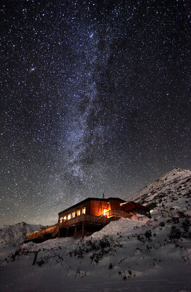 Milky way over winter mountain landscape with cottage, Slovakia 