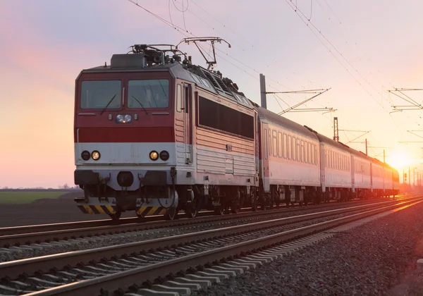 Comboio de passageiros na estrada de ferro ao pôr do sol — Fotografia de Stock