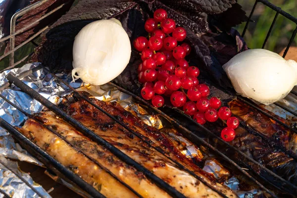 Roasted fish cooked on the open fire with garlic and currant