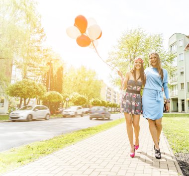 İki genç sarışın kadın renkli lateks balonlar holding.