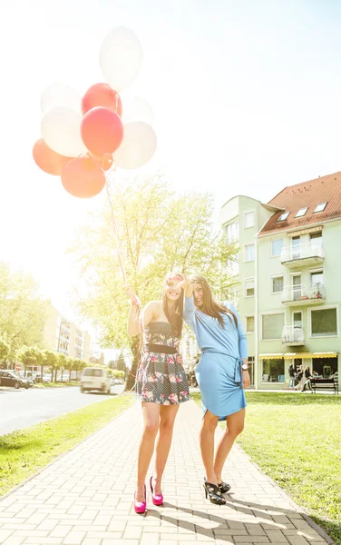 Dos mujeres rubias jóvenes sosteniendo globos de látex de colores . —  Fotos de Stock