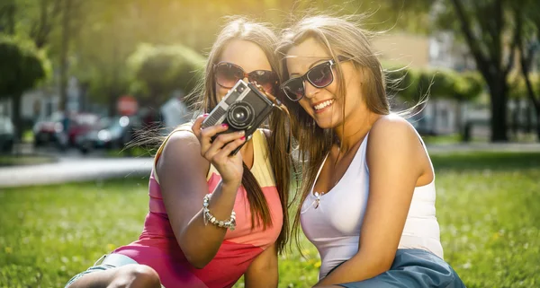 Dos hermosas mujeres jóvenes usando una cámara vintage — Foto de Stock