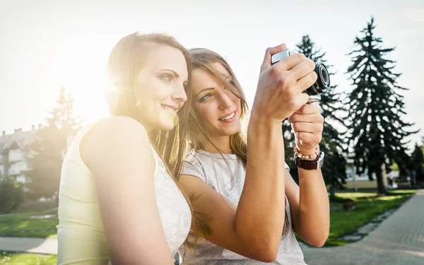 Due belle giovani donne che utilizzano una fotocamera vintage — Foto Stock