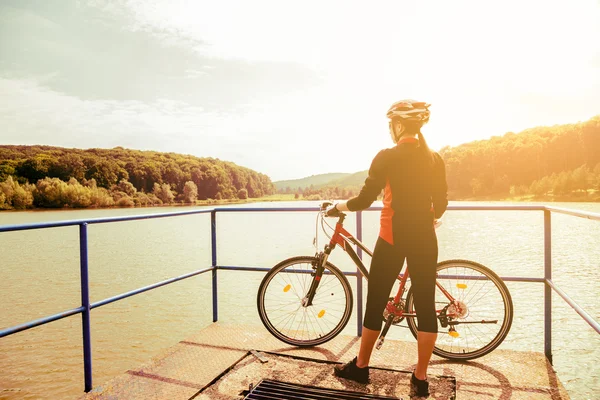 Happy young woman riding a bicycle outside. Royaltyfria Stockfoton