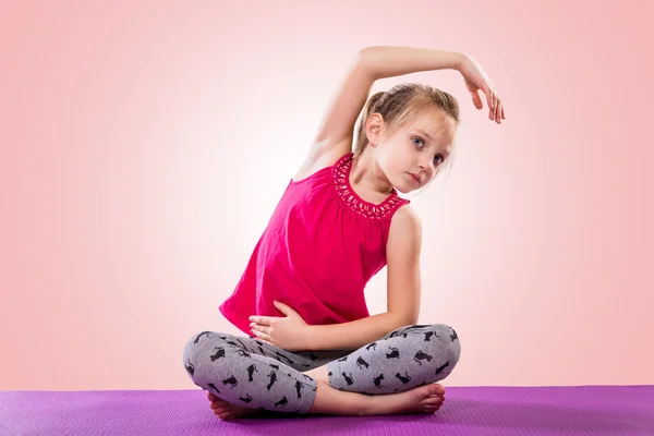 Liten flicka sitter i yogaställning — Stockfoto