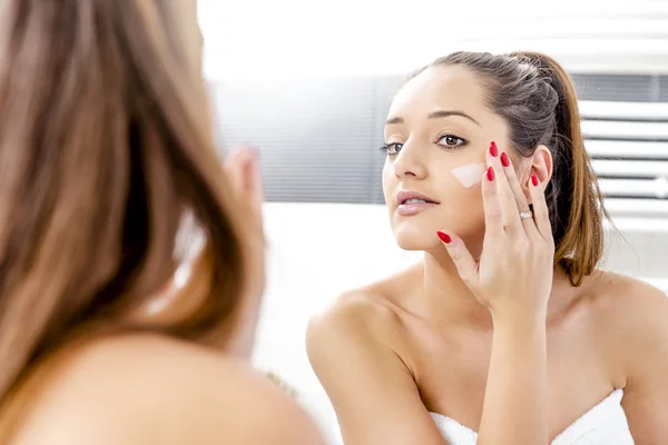 Fille attrayante mettant crème anti-âge Images De Stock Libres De Droits