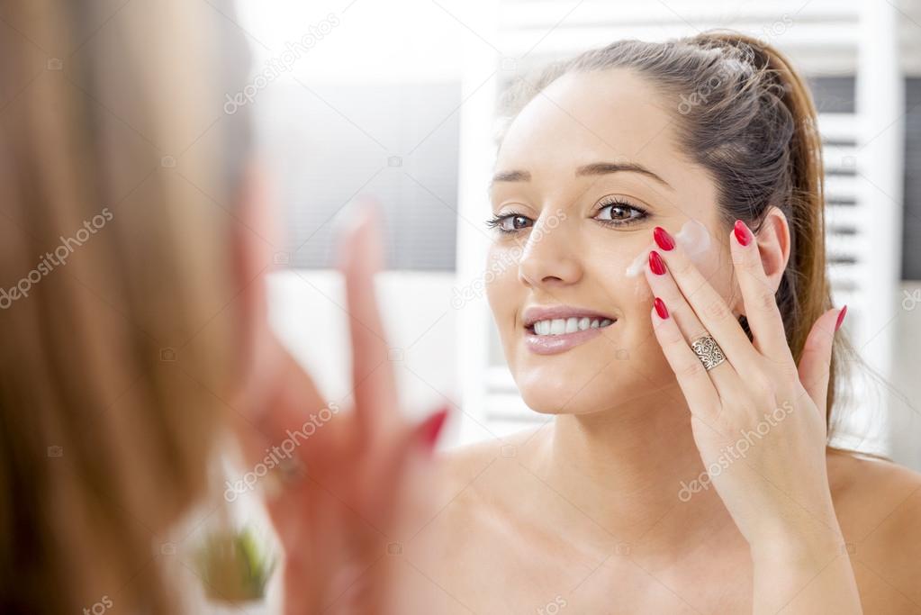 Attractive girl putting anti-aging cream