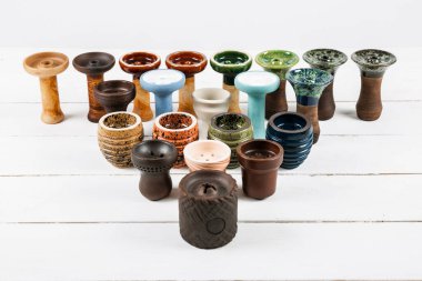 Beyaz ahşap arka planda nargile kaseleri var. Farklı şekil ve renkler.