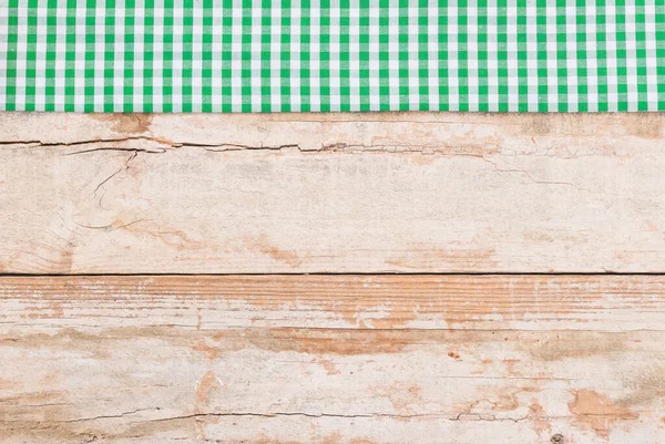 Rustic wooden table surface with green checkered cloth, top view