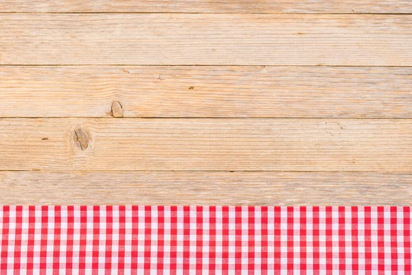 Red checked table-cloth on wooden background with copy space, top view