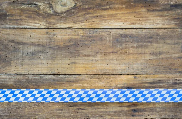 Bavarian or Oktoberfest background on wooden rustic brown table top with blue white traditional pattern banner. Copy space for text.
