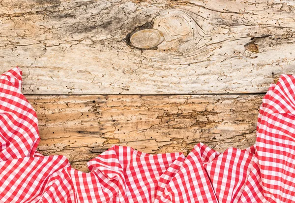 Rustic old wooden table surface with red checkered cloth, top view