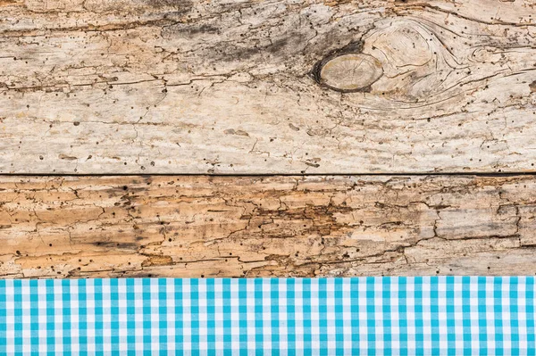 Rustic wooden table surface with blue checkered cloth, top view