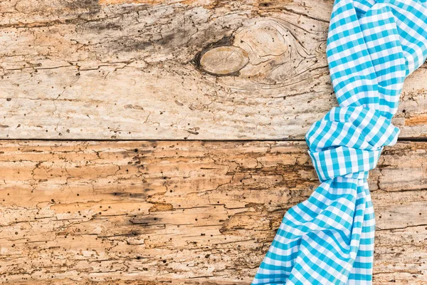 Rustic wooden table surface with blue checkered cloth, top view