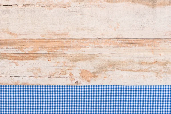 Rustic wooden table surface with blue checkered cloth, top view