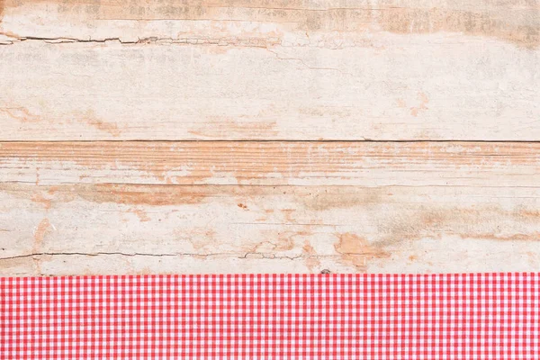 Rustic wooden table surface with red checkered cloth, top view