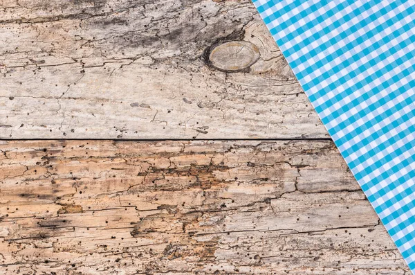 Rustic blue checked table-cloth fabric on old wooden table, top view, copy space