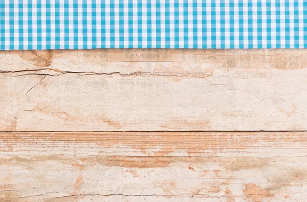 Rustic wooden table surface with blue checkered cloth, top view