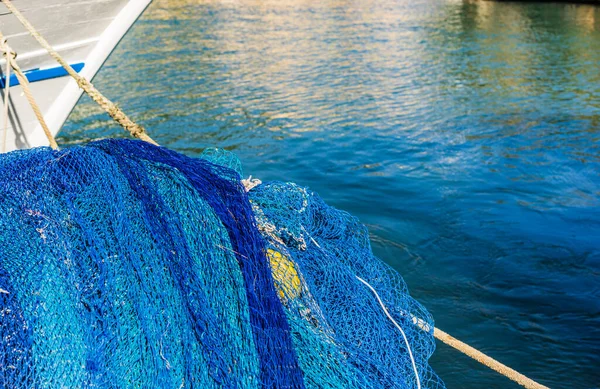 Blue commercial fishing net at harbor with boat and sea water background