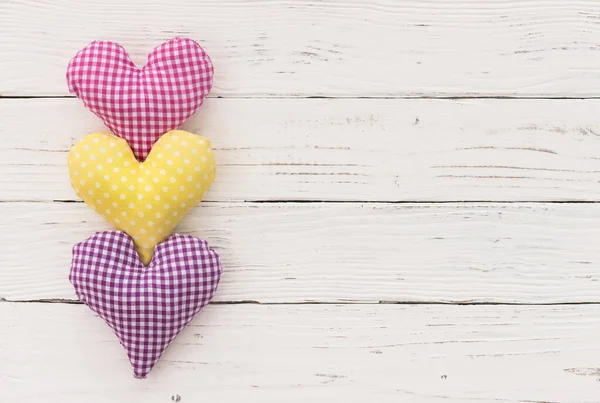 Three romantic hearts on white wood background with copy space