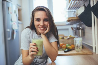 Genç bir kadın mutfağında meyve püresi tutuyor.