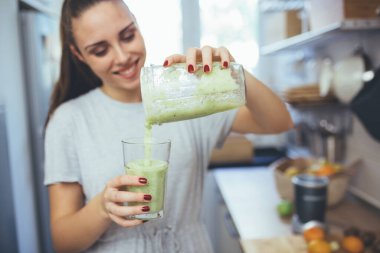 Genç bir kadın mutfağında meyve suyu hazırlıyor.
