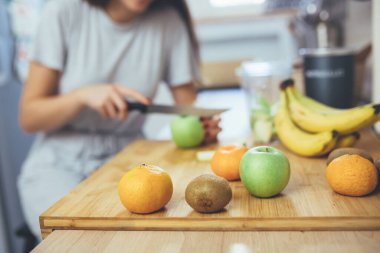 Genç bir kadın mutfağında meyve suyu hazırlıyor.
